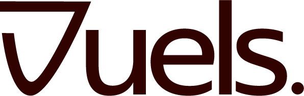 A vintage wooden desk with a mirror in the corner of a room with patterned wallpaper.