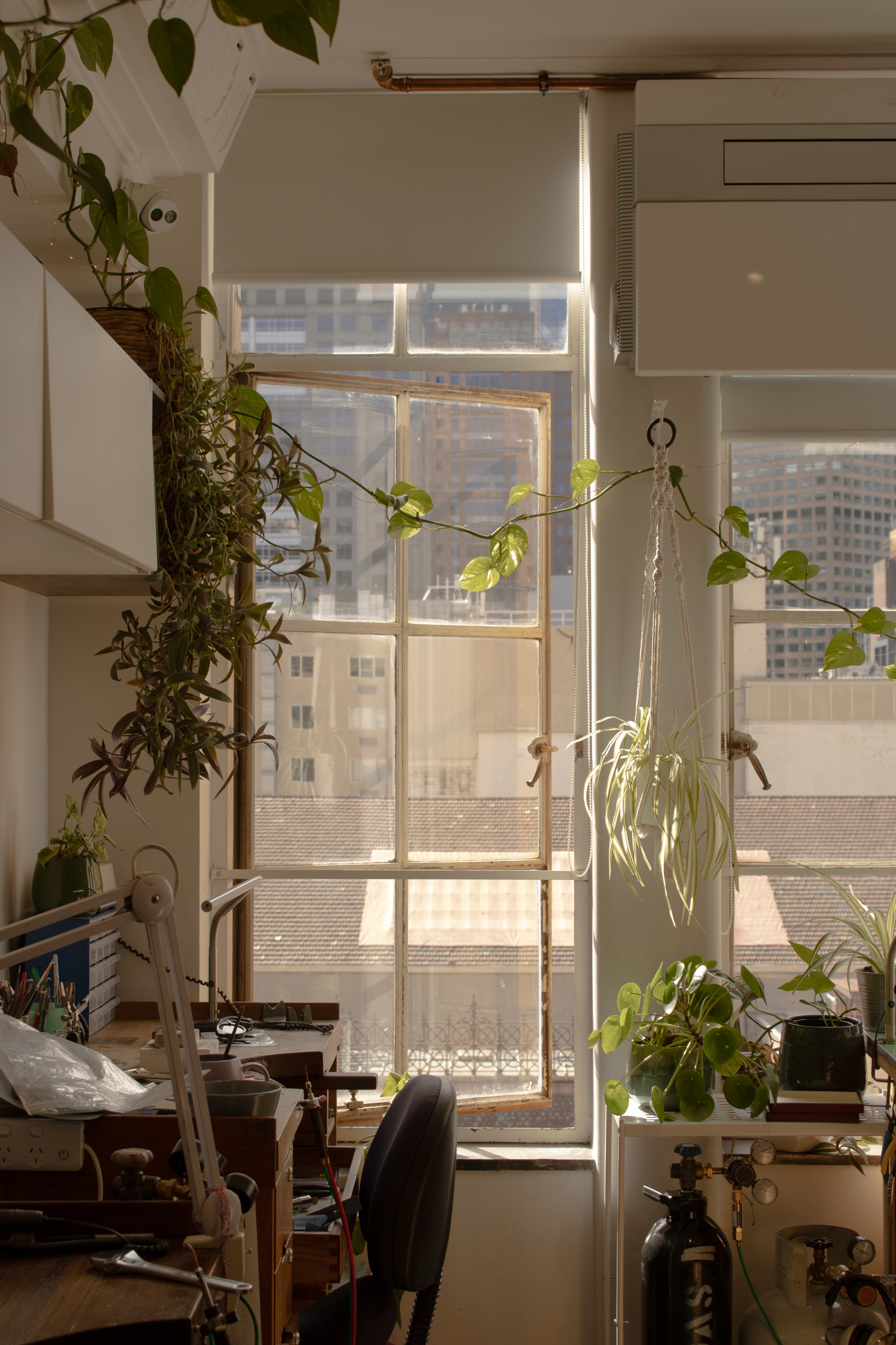 A vintage wooden desk with a mirror in the corner of a room with patterned wallpaper.