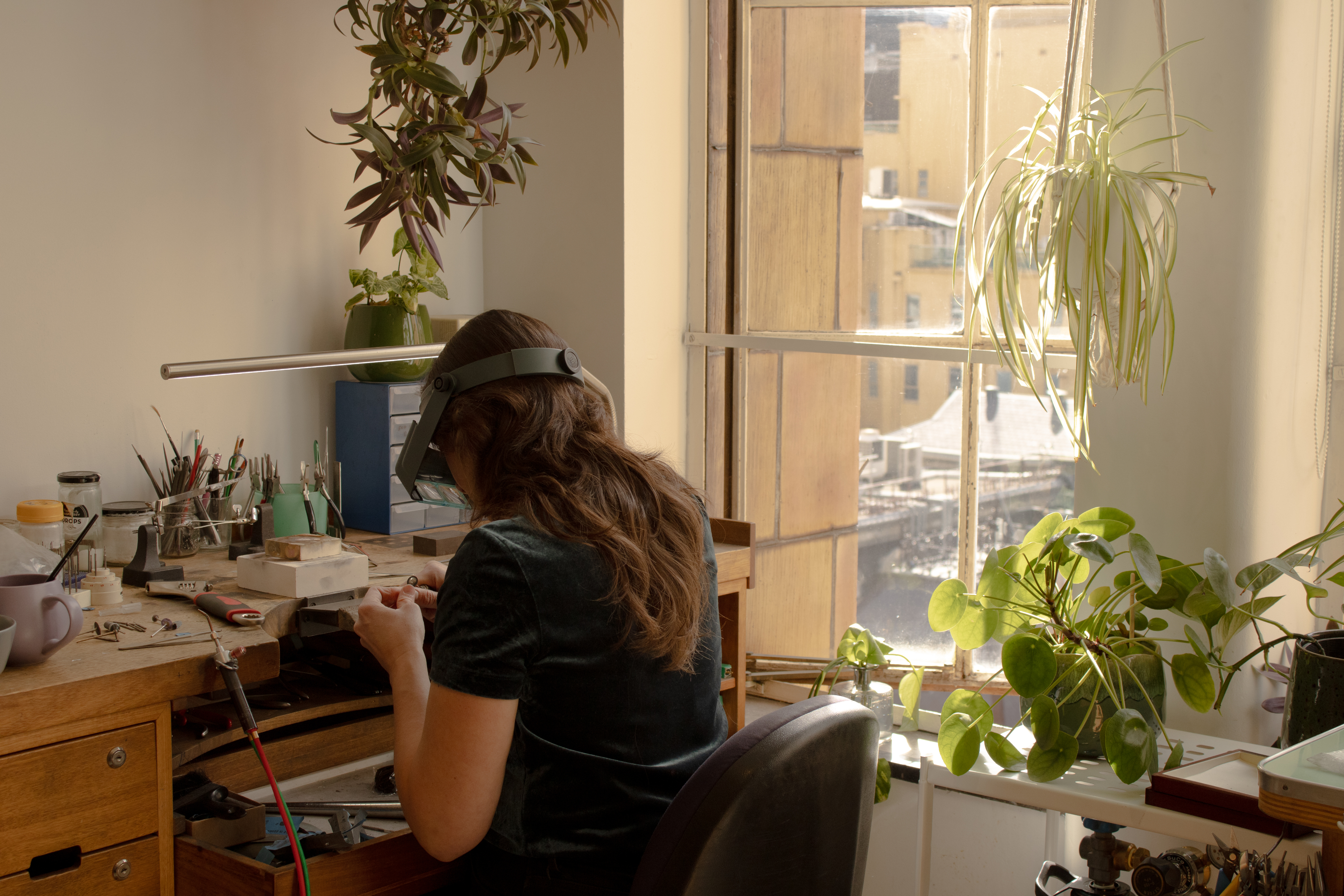 A vintage wooden desk with a mirror in the corner of a room with patterned wallpaper.